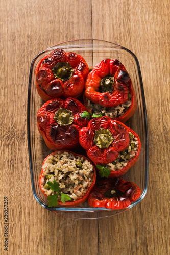 ready baked stuffed peppers in a glass baking dish on the wooden table. healthy vegan cuisine for the whole family. comfort food