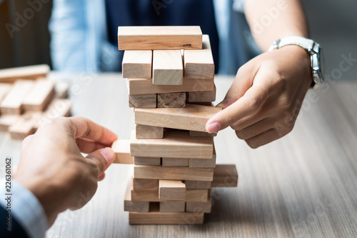 Businessman and Businesswoman hand placing or pulling wooden block on the tower. Business planning, Risk Management, Solution, strategy , Partnership and Cooperation Concepts