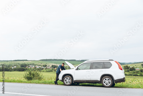 man stand near broken car with opened hood. emergency service