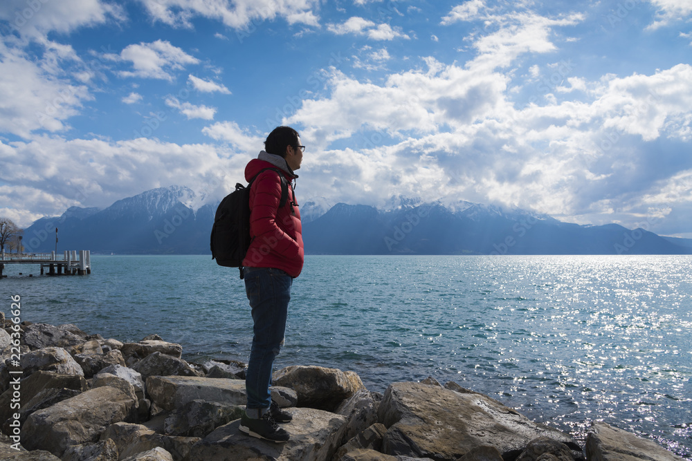 A journey man standing on a rock and look at mountains and lake, lake Geneva, Vevey, Switzerland in Freedom and Adventure concept