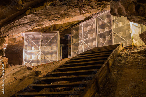 Valokuva Large wheels of cheddar cheese on racks maturing or ageing inside a cave