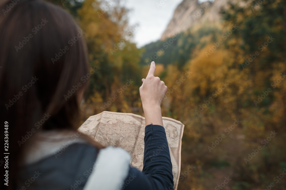 Portrait of a girl with an old map on the background of autumn mountains