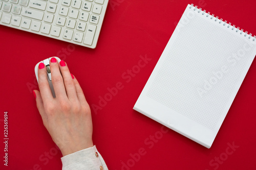 red Desk, woman hands, girl working at the computer, red background with copy space, for advertisement, top view