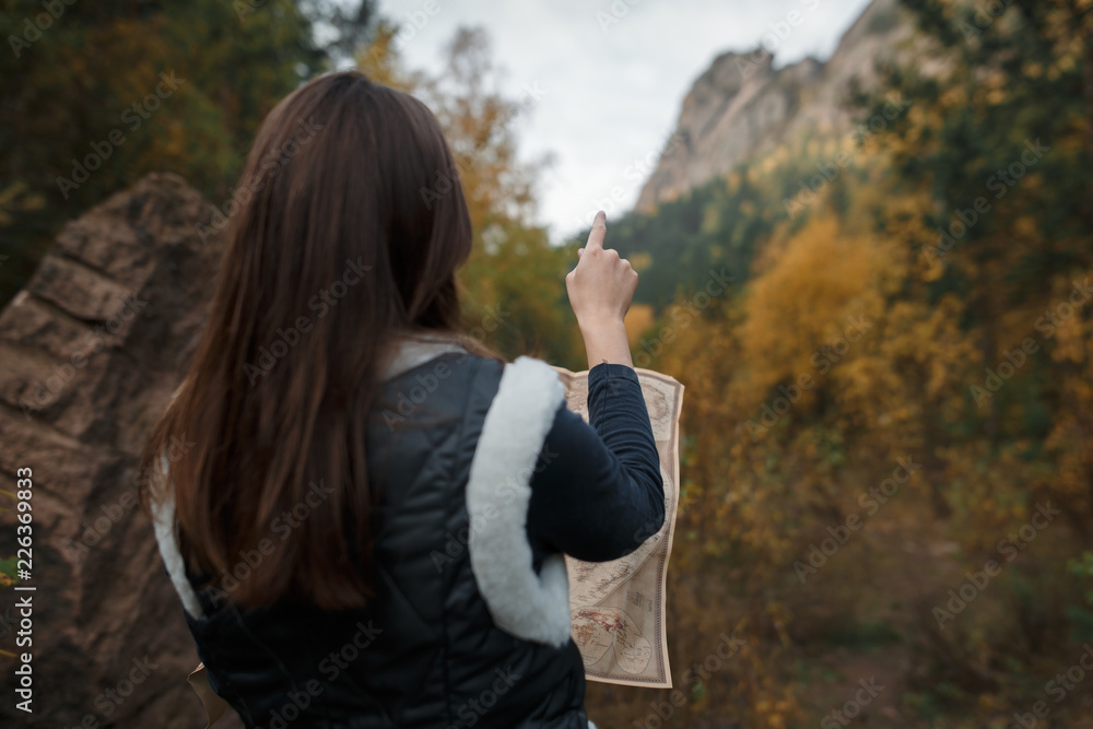 Portrait of a girl with an old map on the background of autumn mountains