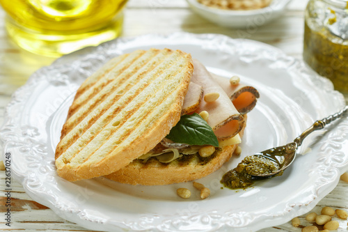 Delicious sandwich with baked ham, cheese, pesto sauce and pine nuts. Healthy snack for gourmets