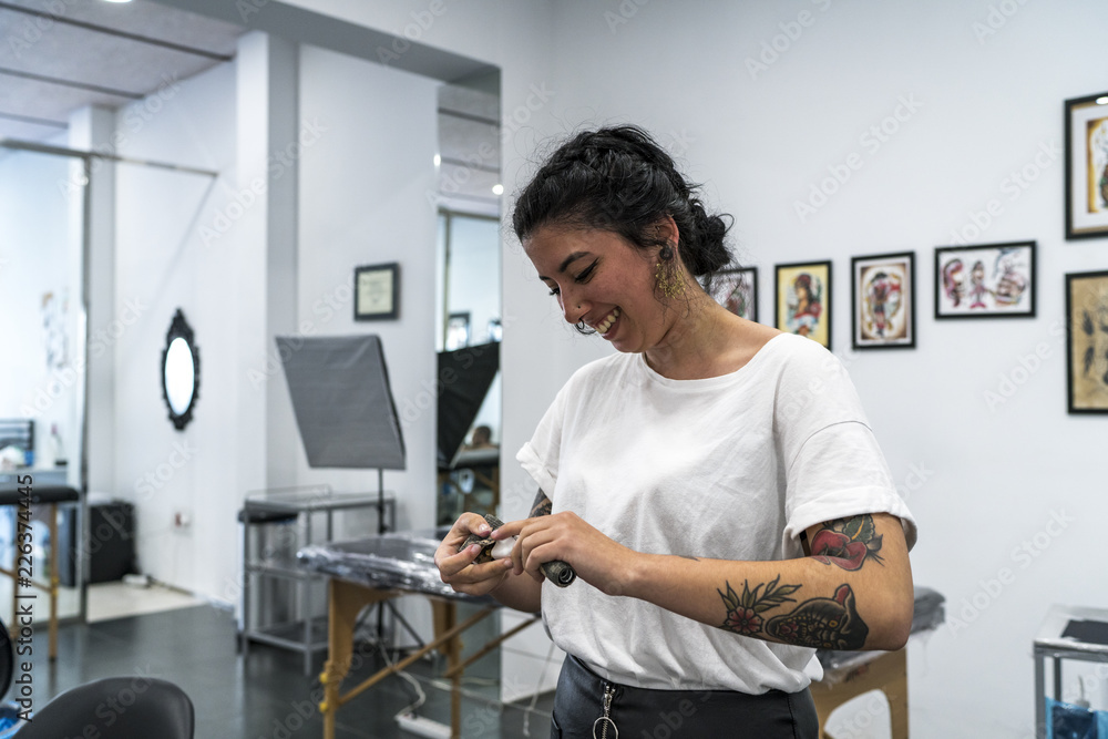 Young woman tattooed preparing the tattoo machine.