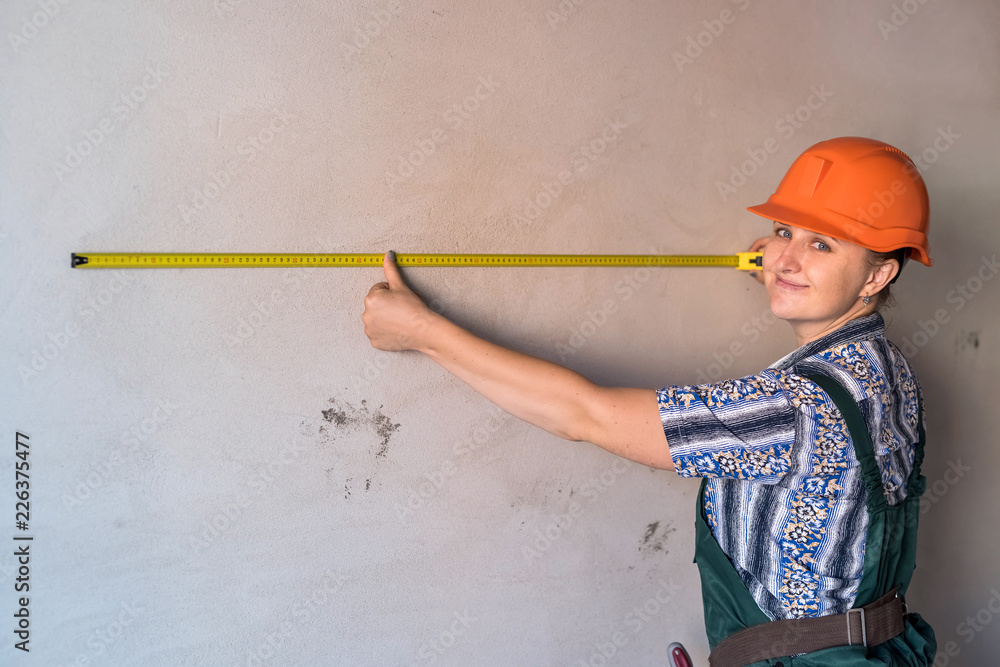 Beautiful builder with measuring tape in new apartment Beautiful builder with measuring tape in new apartment