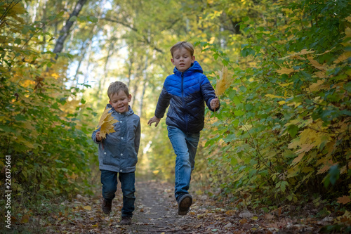 two happy boys run through the autumn Park