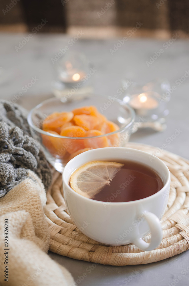 Cup of tea and dried apricots on a table, candles and knited blanket. Cup of tea and dried apricots on a table, candles and knited blanket.