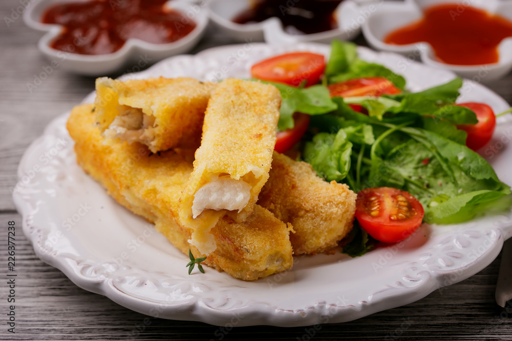 Fish sticks fried in breadcrumbs served with salad on a plate Fish sticks fried in breadcrumbs served with salad on a plate