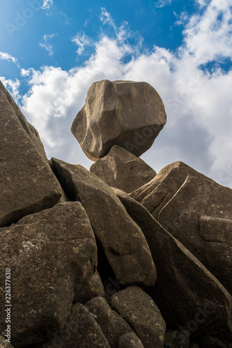 Closeup view of Omu di Cagna (Uomo di Cagna) on the island of Corsica. The granite rock is balanced at the top of a peak on the mountain of Cagna, surrounded by clouds and blue sky. photo