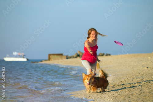 girl playing with a dog on the beach photo