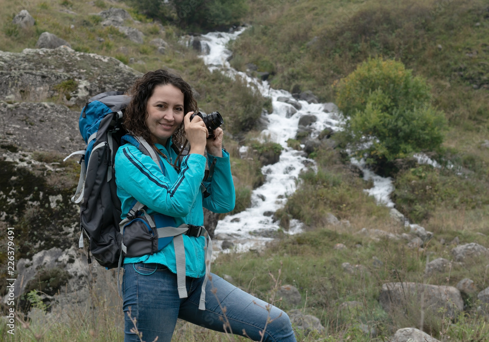 A woman photographs the landscape in the mountains. A woman photographs the landscape in the mountains.
