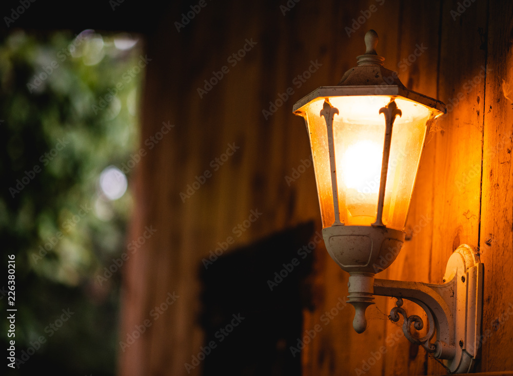 Bright orange lamp against a cabin wall in the middle of a wood in Autumn, England