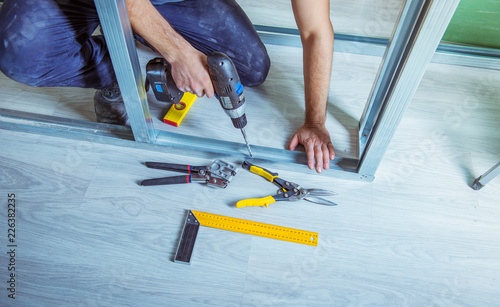 Drywall plaster stud crimpers in action. A person holding and using stud crimping tool in hand while building a metal drywall construction in a house during renovation photo