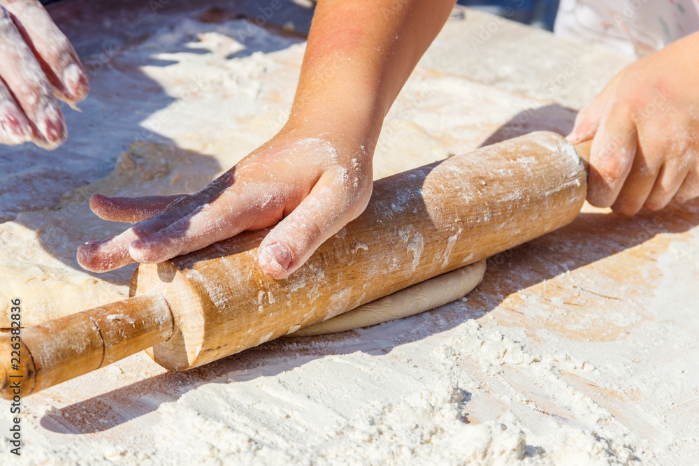 Woman's hands rolling out a dough with rolling pin