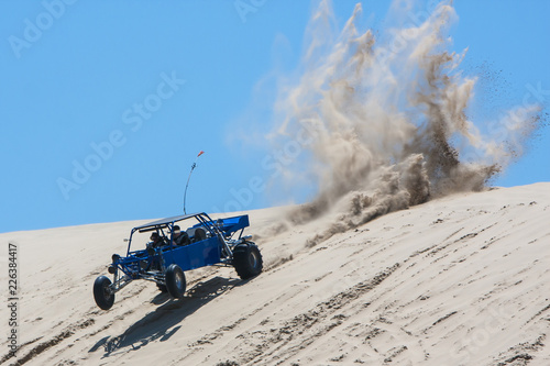 Speeding dune buggy on giant sand dune. photo