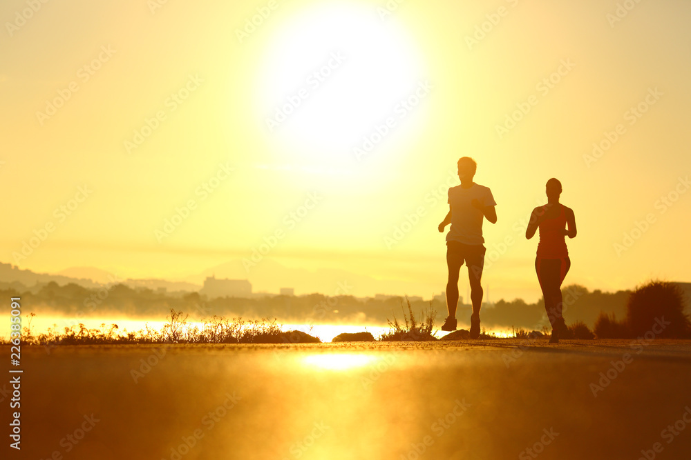 Man and woman silhouettes running at sunrise