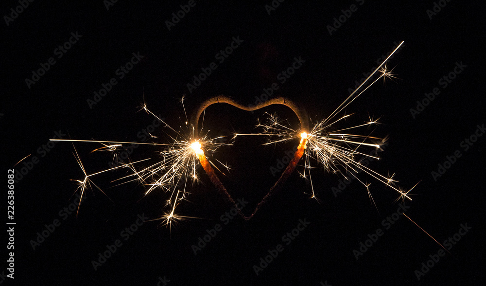 Heart shape sparkler burning, isolated on black background. Party background. Copy space, room for text.