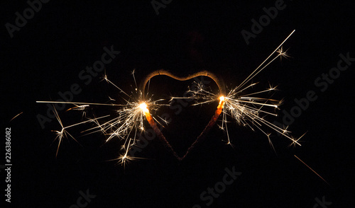 Heart shape sparkler burning  isolated on black background. Party background. Copy space  room for text.