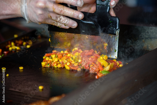 Closeup of chief-cooker mixing fried vegetables on pan
