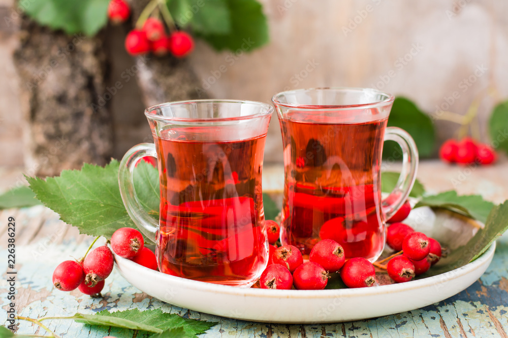 Hot tea from hawthorn berries in transparent glasses on a wooden table Hot tea from hawthorn berries in transparent glasses on a wooden table