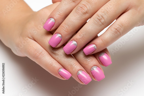 pink manicure with silver on short square nails on a white background close-up
