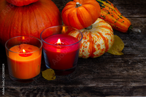 Fall ripe of pumpkins with two burning candles on wooden table