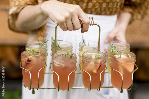 Woman holding drink caddy with cocktails in mason jars