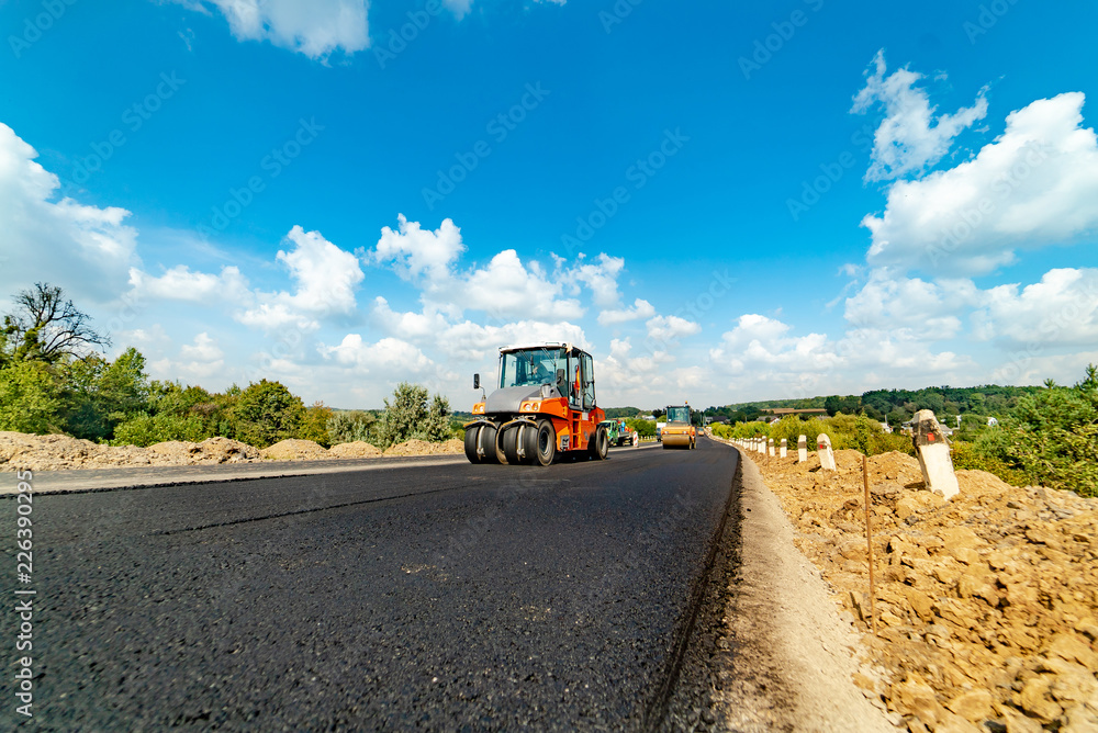 professional equipment lays and aligns fresh asphalt on the highway in the summer. Vibratory rollers in the construction and repair works of roads professional equipment lays and aligns fresh asphalt on the highway in the summer. Vibratory rollers in the construction and repair works of roads