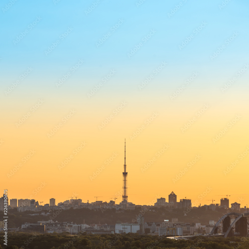 City sunset with TV tower and buildings silhouette on orange skyline