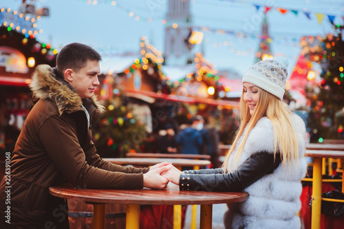 happy loving couple enjoying Christmas or New year Holidays outdoor, walking on city festive market with street food