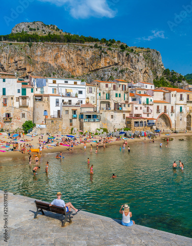 Cefalù waterfront with peole relaxing on a sunny summer day. Sicily, southern Italy.