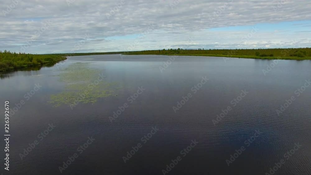 Flying over Surface of Lake. The quadcopter is flying low over the forest lake. The lake is located in Siberia, in the taiga and forest Flying over Surface of Lake. The quadcopter is flying low over the forest lake. The lake is located in Siberia, in the taiga and forest