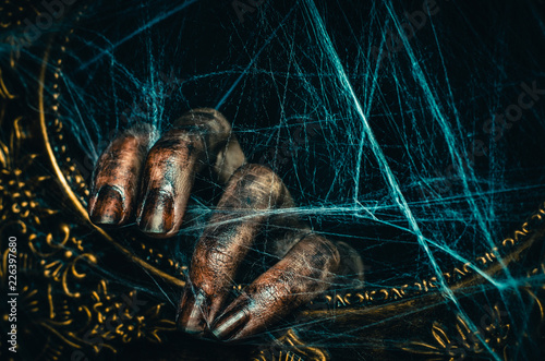 Bloody dirty dead hand keeps an ancient frame covered with old creepy spiderweb