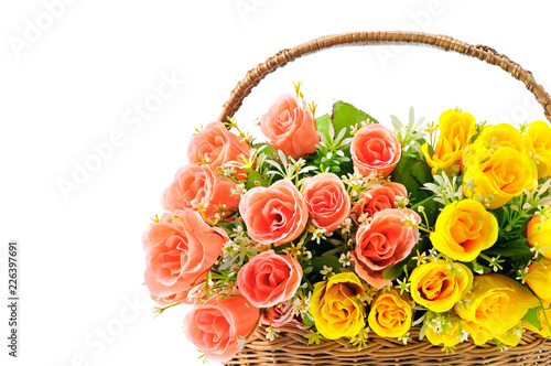 Silk red and yellow roses in a basket isolated on white background. Free space for text.
