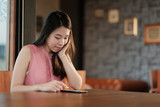 Young asian woman looking her mobile phone in coffee cafe.