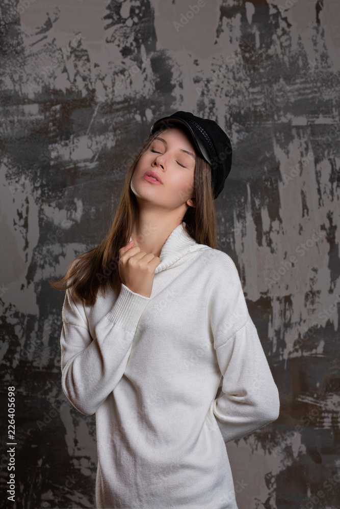 Fototapeta premium Test shoot of sensual brunette girl posing in stylish cap and knitted dress