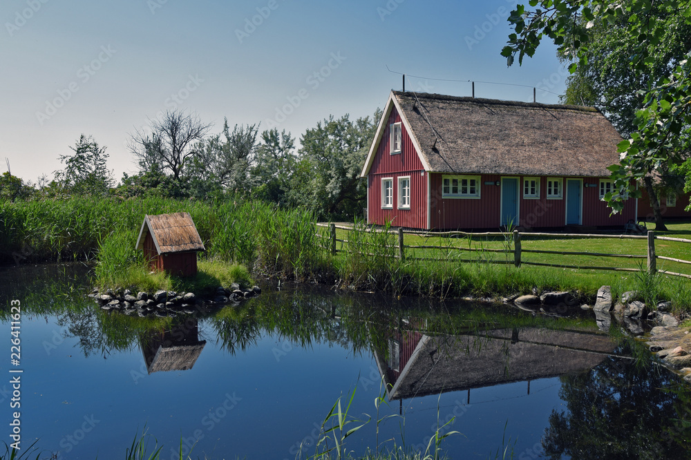Wooden house with thatched roof by a duck pond Wooden house with thatched roof by a duck pond