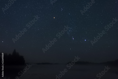 Orion constellation above misty lake. photo