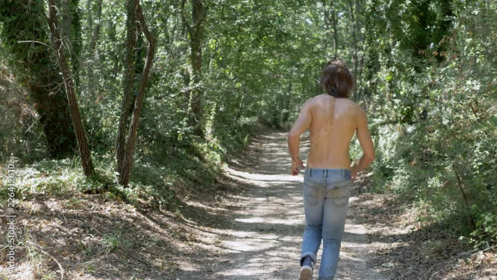 running in the forest. Young man running alone in the wood running in the forest. Young man running alone in the wood