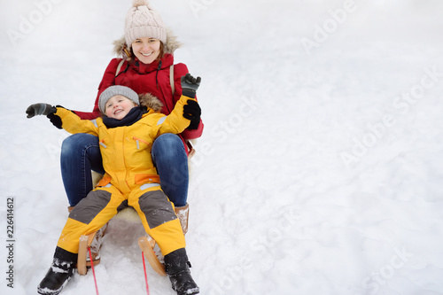 Little boy and mother sliding in the snow