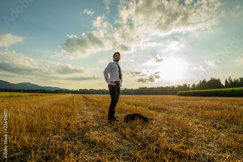 Young confident businessman standing in sawn field