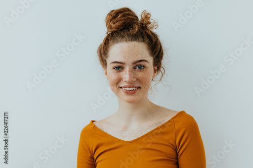 Woman portrait. Style. Beautiful blue eyed girl with freckles is looking at camera and smiling, on a white background