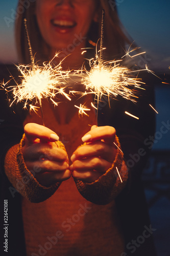 Close-up of happy woman with bright bruning sparklers in the night photo