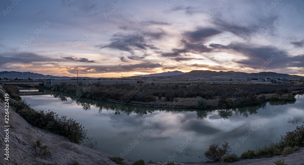 Banner panorama of a dark sunset with clouds reflecting off the river