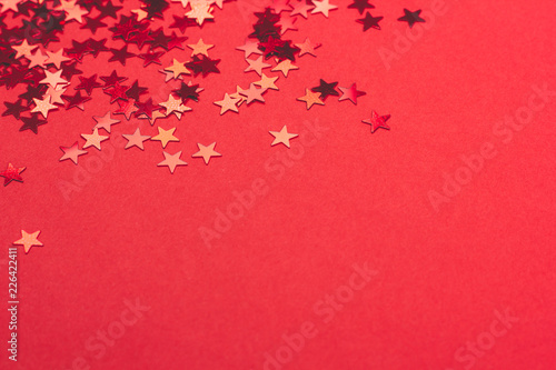 Metallic confetti on festive red paper background.