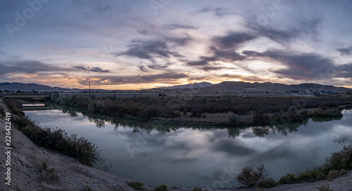 Banner panorama of a dark sunset with clouds reflecting off the river