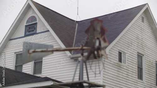 Spinning Windmill Style Weather Vane in Front of Old House , Camera on Slider photo