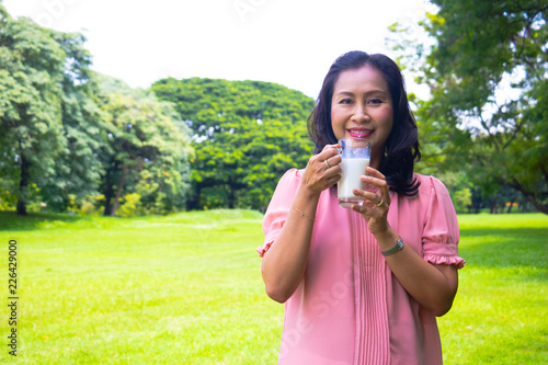 Asian woman relax time in park. She is drinking milk. Life style,Photo concept  exercise and healthy.